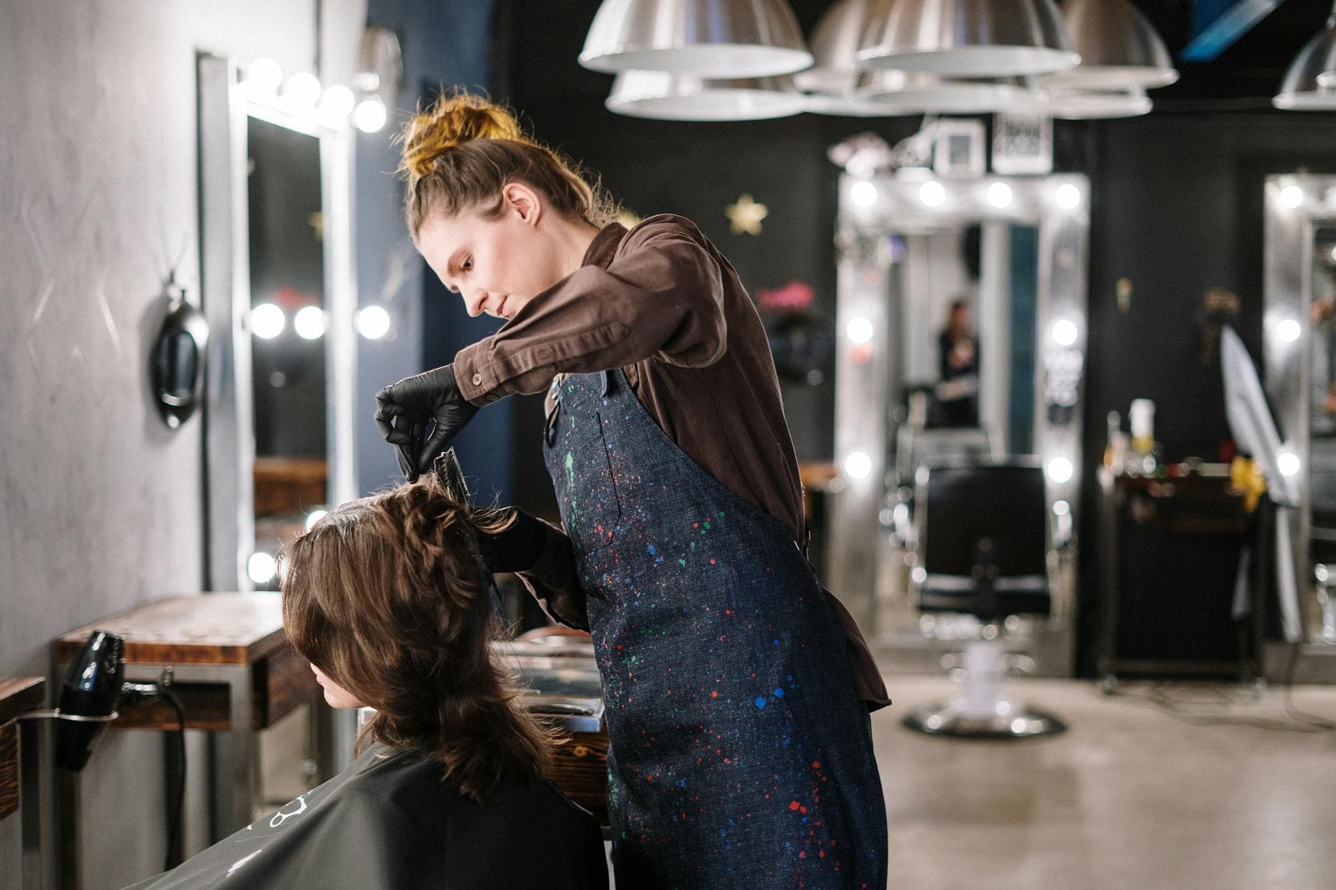 Hair stylist applying color to a client in a modern salon
