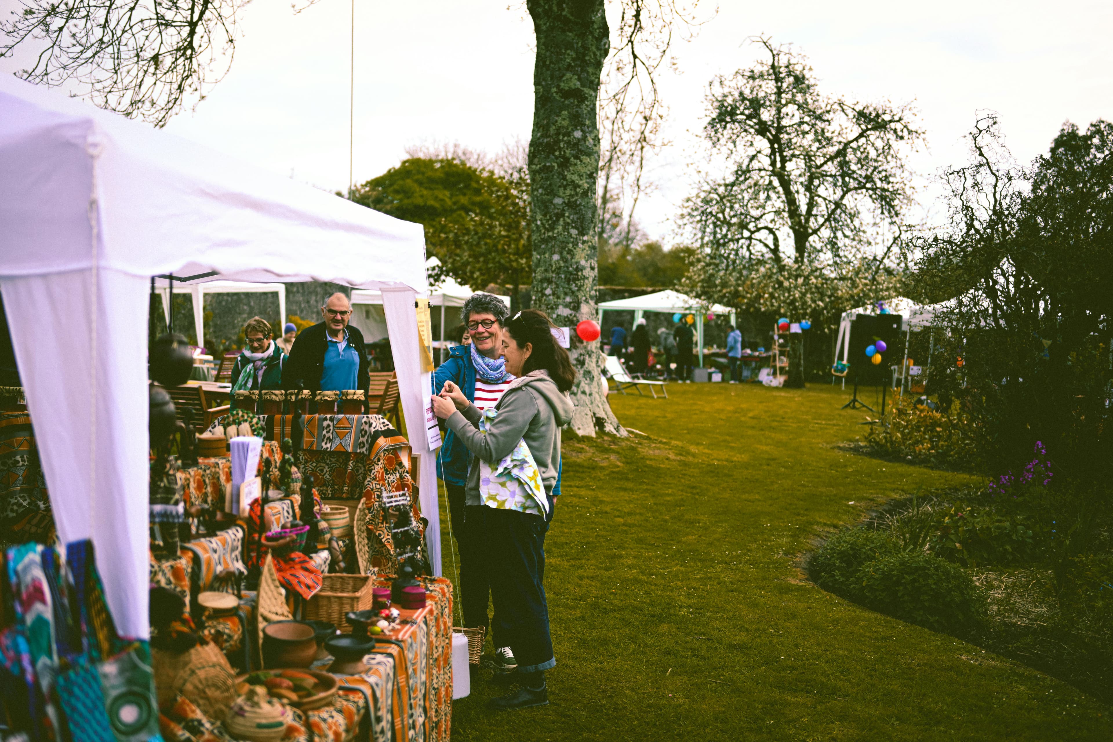 A lively outdoor community market with people browsing stalls